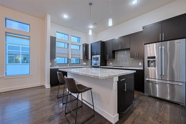 2205 Colorado St, Houston, TX 77007 - kitchen with appliances with stainless steel finishes, dark cabinets, a kitchen island, dark wood finished floors, and a kitchen bar