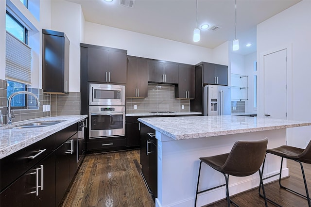 2205 Colorado St, Houston, TX 77007 - kitchen featuring appliances with stainless steel finishes, a center island, a breakfast bar area, hanging light fixtures, and backsplash