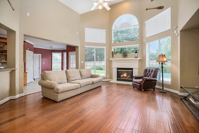 4619 Jade Green Ct, Houston, TX 77059 - living area featuring a towering ceiling, a glass covered fireplace, hardwood / wood-style floors, a ceiling fan, and plenty of natural light