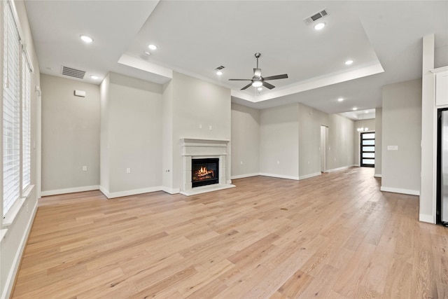 9418 Whispering Bald Cypress Ct, Cypress, TX 77433 - unfurnished living room with a glass covered fireplace, a raised ceiling, ceiling fan, light wood-type flooring, and crown molding