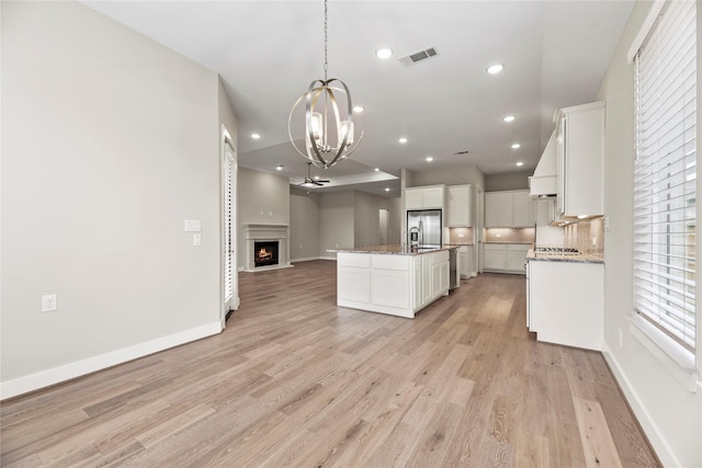 9418 Whispering Bald Cypress Ct, Cypress, TX 77433 - kitchen featuring open floor plan, a chandelier, stainless steel appliances, white cabinetry, and light wood-style flooring