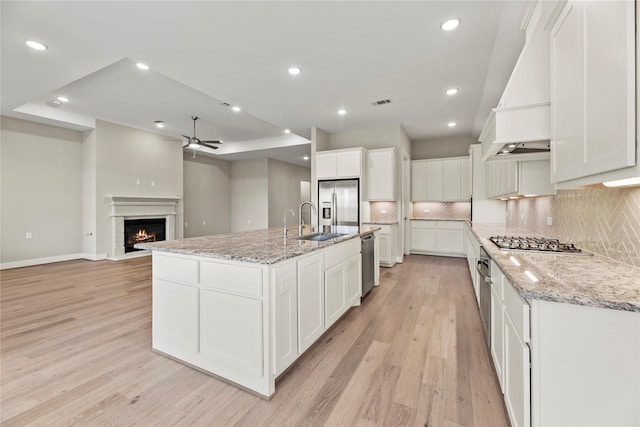9418 Whispering Bald Cypress Ct, Cypress, TX 77433 - kitchen with a ceiling fan, light wood finished floors, custom exhaust hood, appliances with stainless steel finishes, and tasteful backsplash