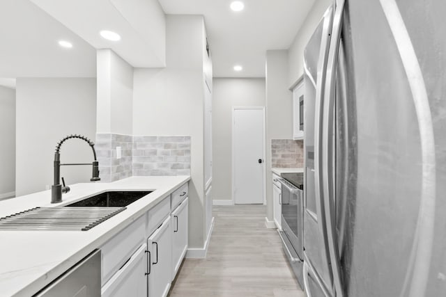 550 Wilcrest Dr Unit 550, Houston, TX 77042 - kitchen featuring appliances with stainless steel finishes, tasteful backsplash, light wood-type flooring, white cabinetry, and recessed lighting