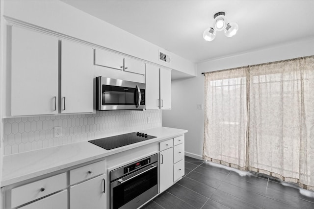 6697 De Moss Dr Unit 697, Houston, TX 77074 - kitchen with appliances with stainless steel finishes, tasteful backsplash, light countertops, white cabinets, and dark tile patterned floors