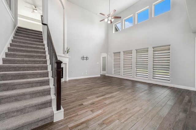 28702 Casen Ranch Ln, Fulshear, TX 77441 - unfurnished living room with a ceiling fan, wood finished floors, a high ceiling, and stairway