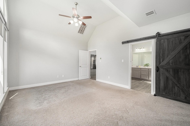 28702 Casen Ranch Ln, Fulshear, TX 77441 - unfurnished bedroom featuring light colored carpet, a barn door, high vaulted ceiling, ensuite bath, and a ceiling fan