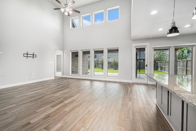28702 Casen Ranch Ln, Fulshear, TX 77441 - unfurnished living room with wood finished floors, a ceiling fan, a high ceiling, and recessed lighting