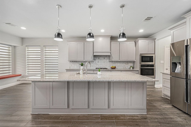 28702 Casen Ranch Ln, Fulshear, TX 77441 - kitchen with appliances with stainless steel finishes, tasteful backsplash, dark wood-style flooring, a kitchen island with sink, and recessed lighting