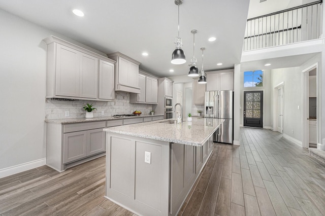 28702 Casen Ranch Ln, Fulshear, TX 77441 - kitchen featuring appliances with stainless steel finishes, light wood-type flooring, an island with sink, tasteful backsplash, and gray cabinets