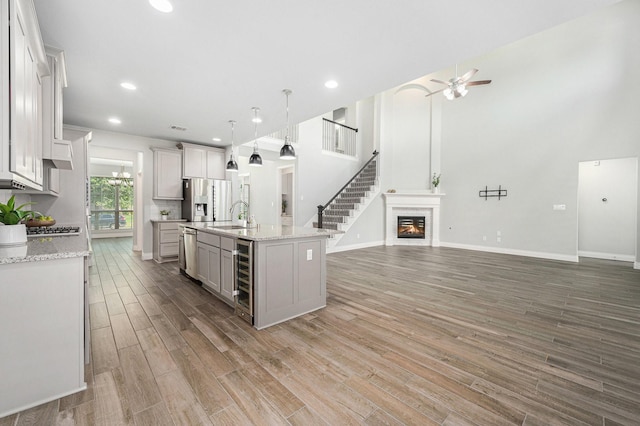 28702 Casen Ranch Ln, Fulshear, TX 77441 - kitchen featuring appliances with stainless steel finishes, open floor plan, ceiling fan, light wood-style floors, and wine cooler