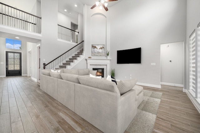 28702 Casen Ranch Ln, Fulshear, TX 77441 - living room featuring a towering ceiling, a fireplace, light wood-style floors, a ceiling fan, and stairway