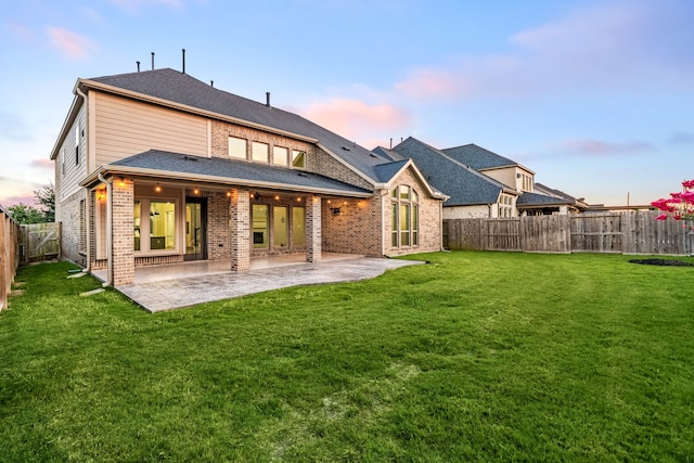 28702 Casen Ranch Ln, Fulshear, TX 77441 - back of property at dusk with brick siding, a patio, and a fenced backyard