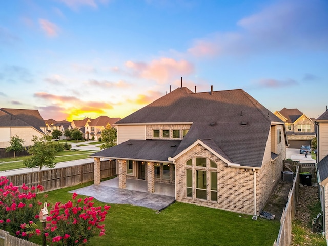 28702 Casen Ranch Ln, Fulshear, TX 77441 - back of property at dusk with a patio, roof with shingles, brick siding, a fenced backyard, and a residential view