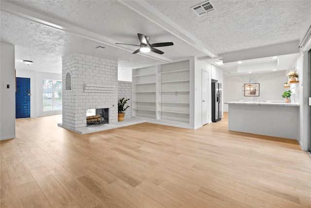 7019 Pyron Way, Houston, TX 77036 - unfurnished living room featuring ceiling fan, a textured ceiling, a fireplace, light wood finished floors, and built in shelves