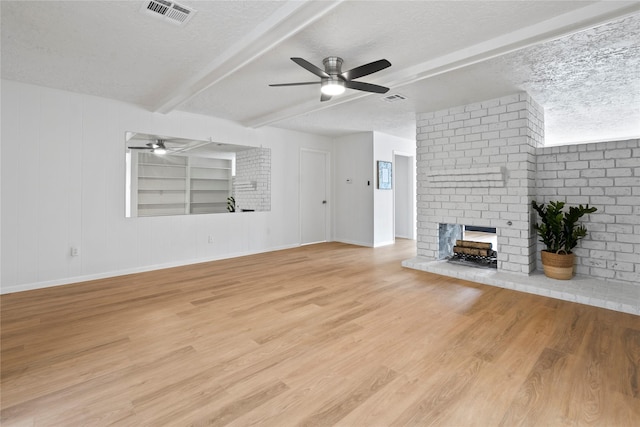 7019 Pyron Way, Houston, TX 77036 - unfurnished living room featuring a brick fireplace, a ceiling fan, beamed ceiling, light wood-style floors, and a textured ceiling