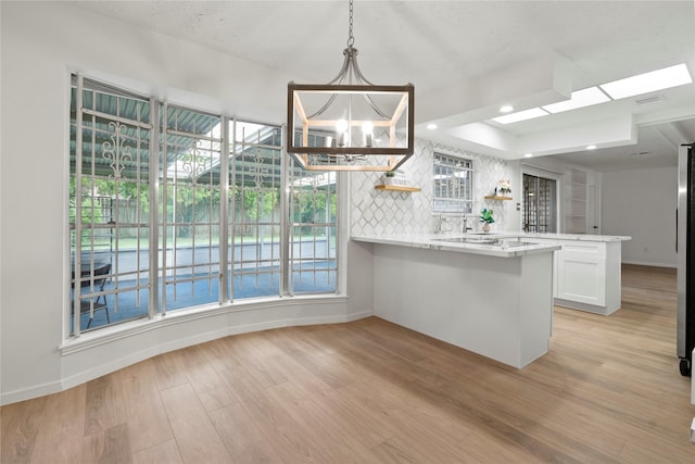 7019 Pyron Way, Houston, TX 77036 - kitchen with a peninsula, open shelves, a chandelier, light wood-style flooring, and white cabinets