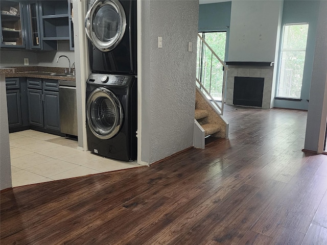 10811 Richmond Ave Unit 40, Houston, TX 77042 - laundry room with stacked washer and clothes dryer, a textured wall, light wood-style floors, and a tile fireplace