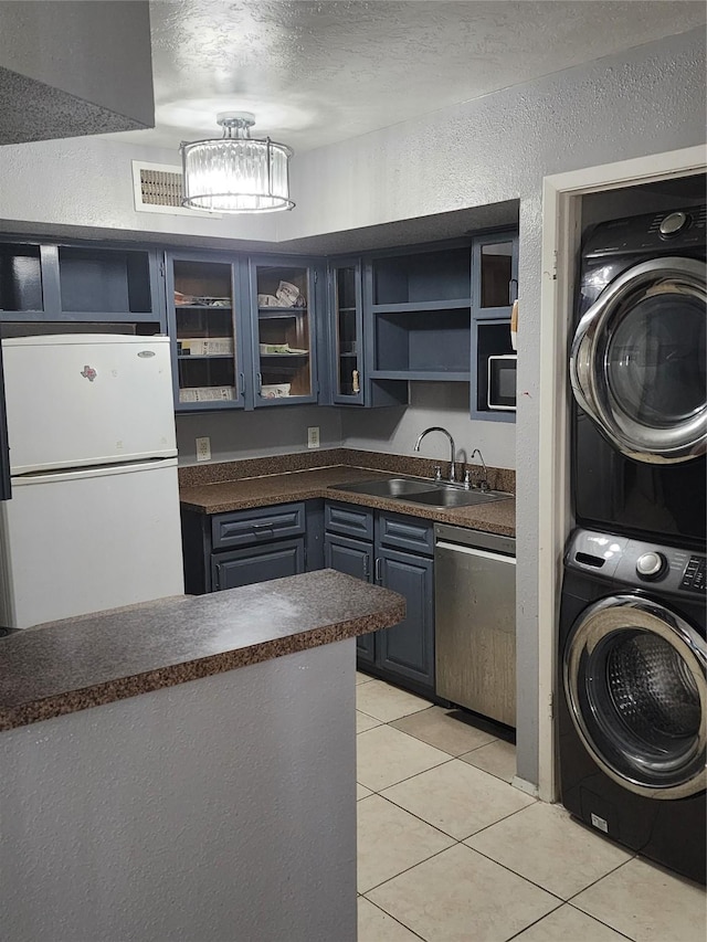 10811 Richmond Ave Unit 40, Houston, TX 77042 - kitchen with freestanding refrigerator, estacked washer and dryer, dark countertops, open shelves, and stainless steel dishwasher