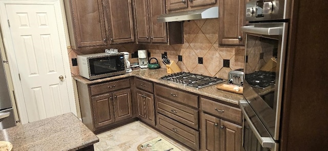 5322 Norborne Ln, Houston, TX 77069 - kitchen with appliances with stainless steel finishes, under cabinet range hood, tasteful backsplash, and dark brown cabinets