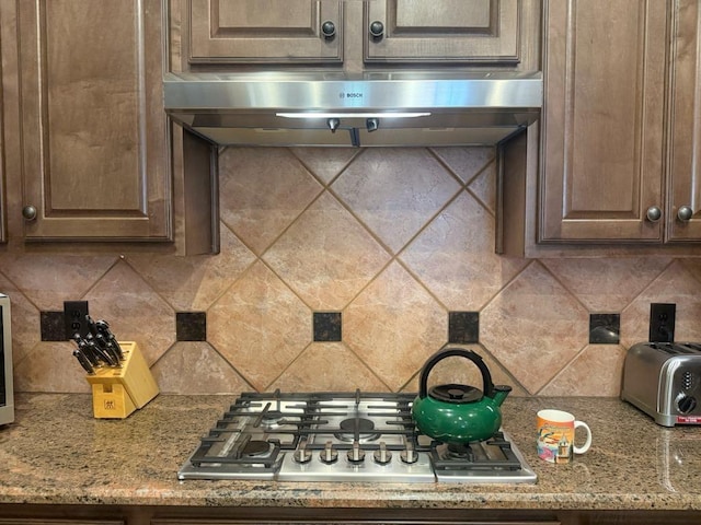 5322 Norborne Ln, Houston, TX 77069 - kitchen featuring stainless steel gas cooktop, under cabinet range hood, tasteful backsplash, and dark brown cabinetry