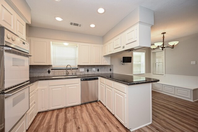 5906 Dumfries Dr, Houston, TX 77096 - kitchen with dishwasher, white double oven, a peninsula, light wood finished floors, and recessed lighting