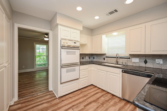 5906 Dumfries Dr, Houston, TX 77096 - kitchen with stainless steel dishwasher, double oven, light wood finished floors, white cabinetry, and backsplash