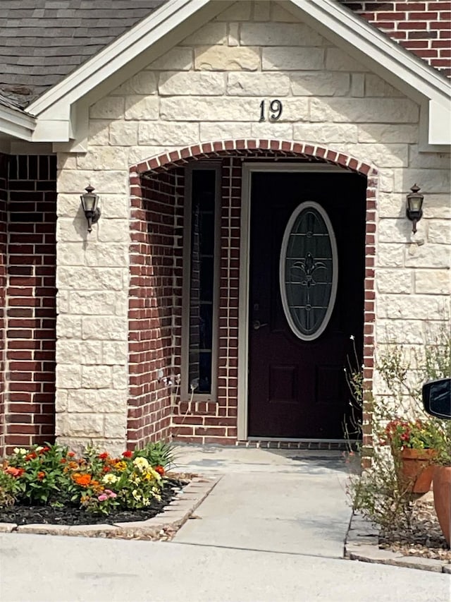 19 Trail Lk, Trinity, TX 75862 - view of exterior entry with stone siding, brick siding, and a shingled roof