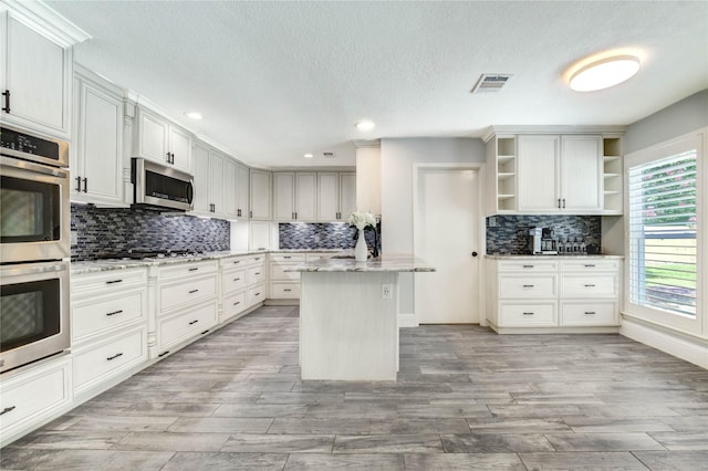 1904 Nursery Rd, The Woodlands, TX 77380 - kitchen featuring appliances with stainless steel finishes, open shelves, decorative backsplash, a textured ceiling, and recessed lighting