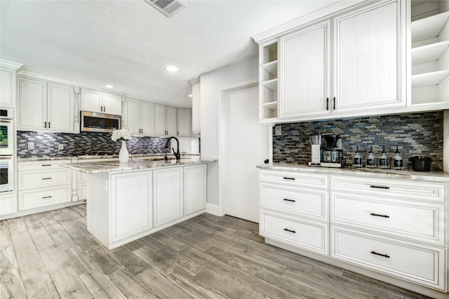 1904 Nursery Rd, The Woodlands, TX 77380 - kitchen featuring open shelves, stainless steel appliances, tasteful backsplash, light wood-style flooring, and white cabinetry