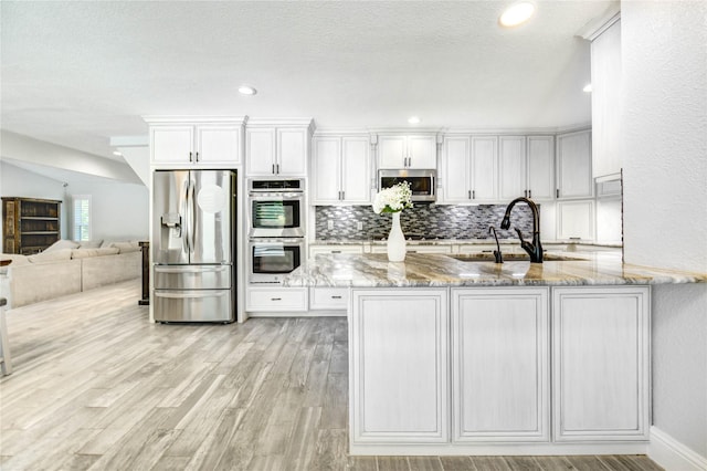 1904 Nursery Rd, The Woodlands, TX 77380 - kitchen featuring stainless steel appliances, light stone countertops, white cabinets, backsplash, and recessed lighting