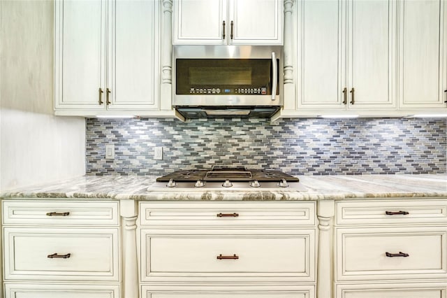 1904 Nursery Rd, The Woodlands, TX 77380 - kitchen with appliances with stainless steel finishes, decorative backsplash, light stone countertops, and cream cabinetry