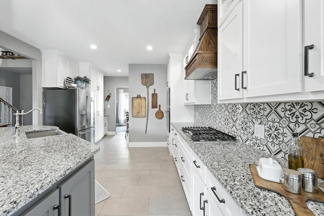 14506 Heron Marsh Dr, Cypress, TX 77429 - kitchen featuring appliances with stainless steel finishes, custom exhaust hood, backsplash, light tile patterned flooring, and light stone countertops