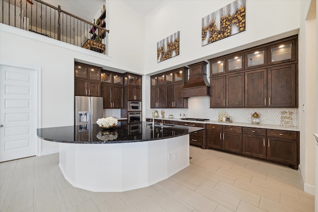 190 Monarch Trl, Sugar Land, TX 77498 - kitchen with stainless steel appliances, premium range hood, dark brown cabinets, dark stone countertops, and a large island with sink
