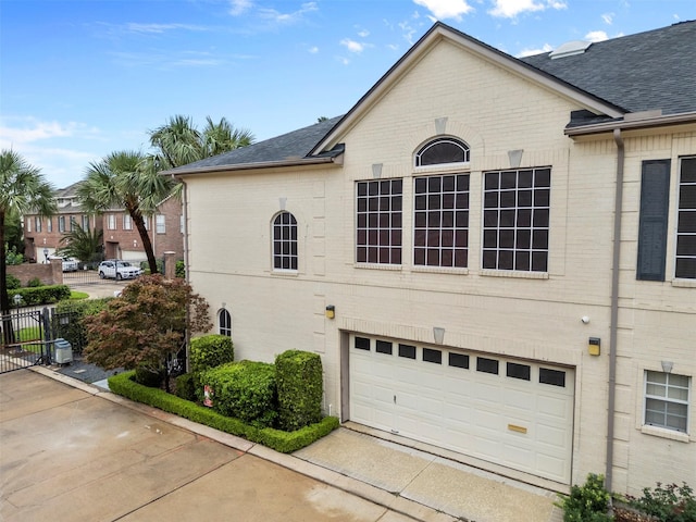 5603 Dolores St, Houston, TX 77057 - view of home's exterior featuring a garage, brick siding, and roof with shingles