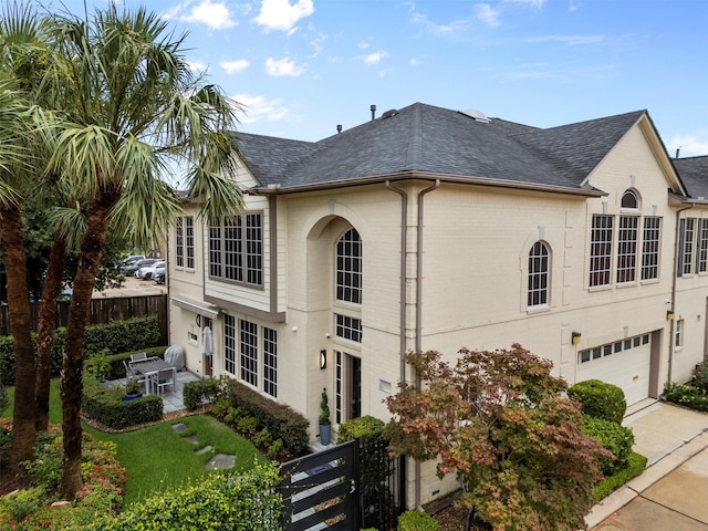 5603 Dolores St, Houston, TX 77057 - view of home's exterior featuring a shingled roof, a garage, a patio, and brick siding