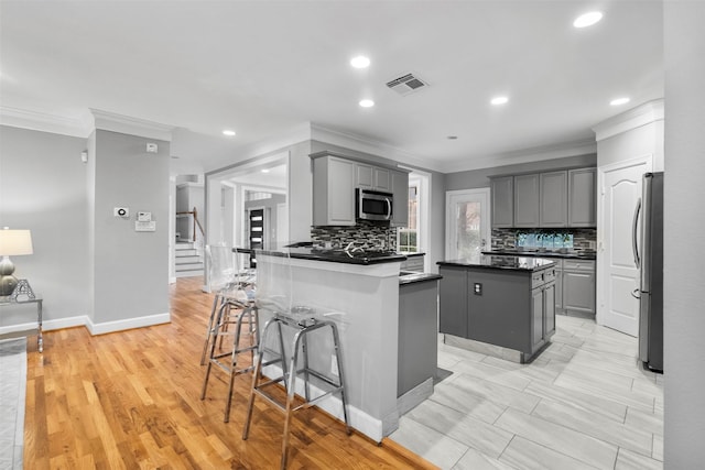 5603 Dolores St, Houston, TX 77057 - kitchen featuring gray cabinetry, stainless steel appliances, ornamental molding, tasteful backsplash, and dark countertops