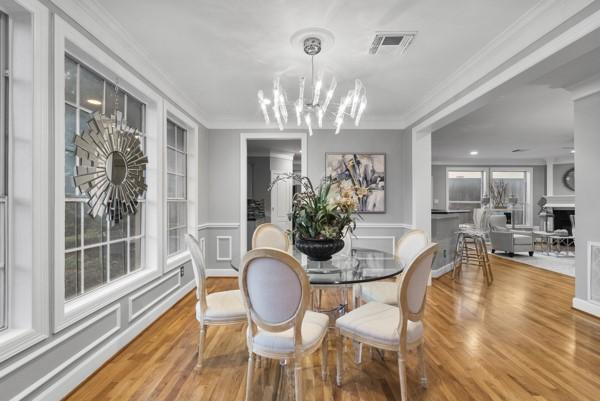 5603 Dolores St, Houston, TX 77057 - dining space with a chandelier, a decorative wall, crown molding, wood finished floors, and a fireplace