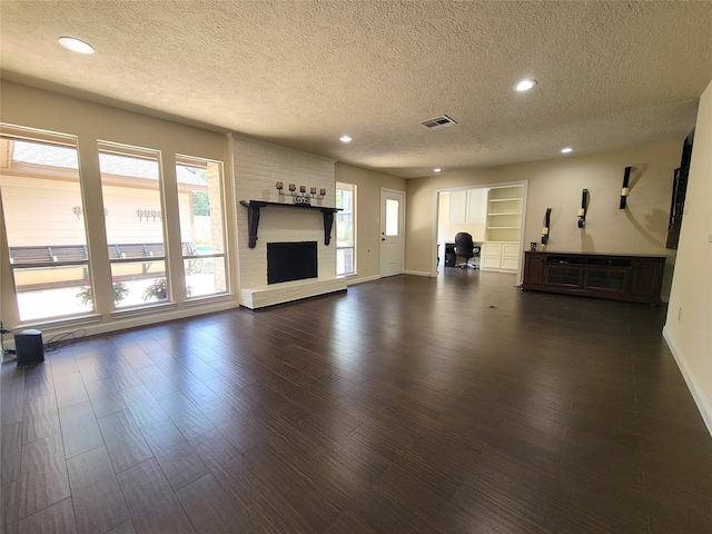 711 Holly Springs Dr, Conroe, TX 77302 - unfurnished living room featuring a textured ceiling, recessed lighting, dark wood finished floors, and a fireplace