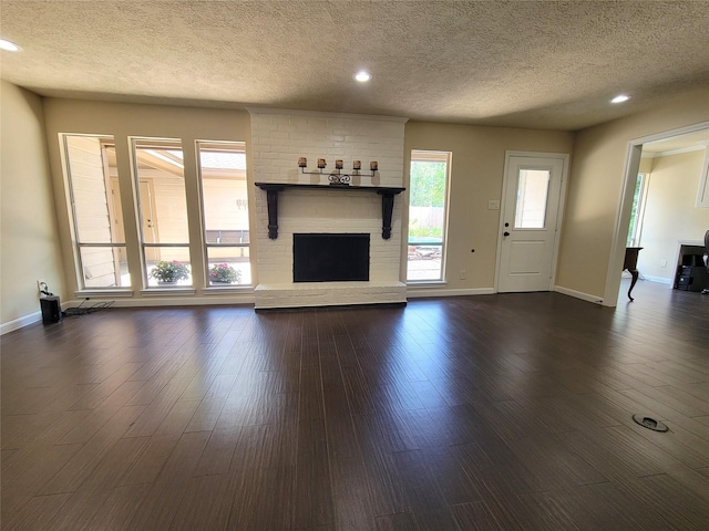 711 Holly Springs Dr, Conroe, TX 77302 - unfurnished living room with a textured ceiling, a brick fireplace, recessed lighting, and dark wood-style flooring