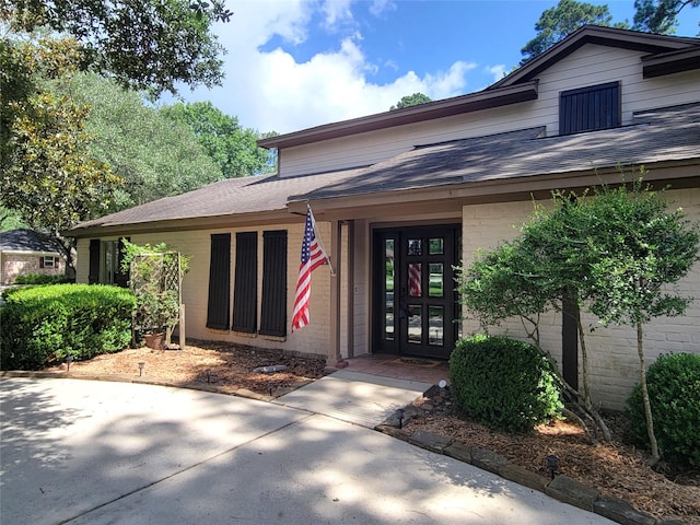 711 Holly Springs Dr, Conroe, TX 77302 - view of exterior entry with french doors, brick siding, and roof with shingles