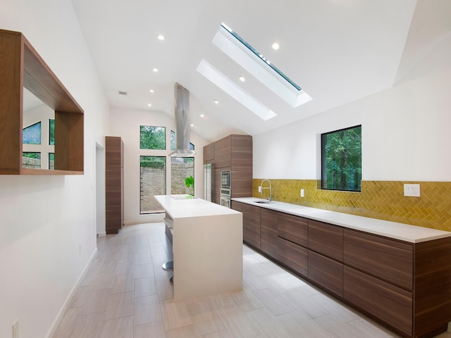 2812 Crossvine, The Woodlands, TX 77380 - kitchen featuring modern cabinets, lofted ceiling, a kitchen island, a skylight, and light countertops