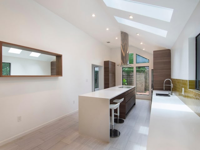 2812 Crossvine, The Woodlands, TX 77380 - kitchen featuring a skylight, modern cabinets, vaulted ceiling, light countertops, and a large island with sink