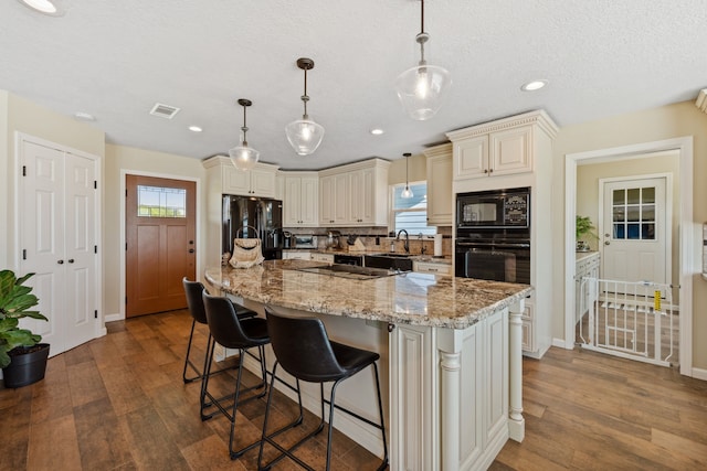 11320 Cedar Gully Rd, Beach City, TX 77523 - kitchen with black appliances, dark wood-style floors, cream cabinetry, light stone counters, and recessed lighting