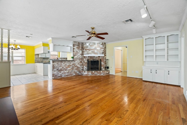 2731 Manila Ln, Houston, TX 77043 - unfurnished living room featuring a ceiling fan, light wood-style floors, a textured ceiling, a chandelier, and a fireplace