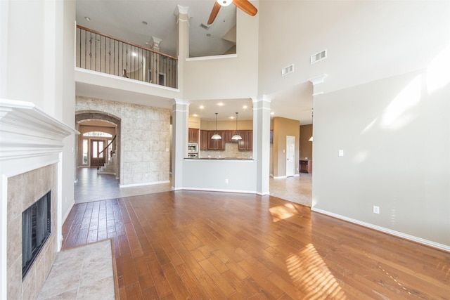 18219 S Austin Shore Dr, Cypress, TX 77433 - unfurnished living room featuring a fireplace, decorative columns, a ceiling fan, light wood-style floors, and stairway