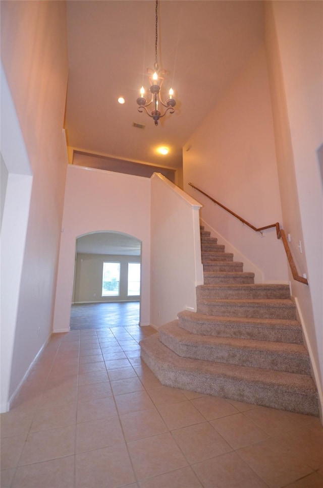 6906 Grant Dr, Magnolia, TX 77354 - stairs featuring a towering ceiling, tile patterned flooring, arched walkways, a chandelier, and recessed lighting