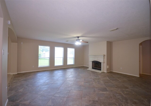 6906 Grant Dr, Magnolia, TX 77354 - unfurnished living room with ceiling fan, arched walkways, and a fireplace with raised hearth