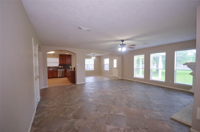 6906 Grant Dr, Magnolia, TX 77354 - unfurnished living room featuring ceiling fan, arched walkways, and stone finish floors
