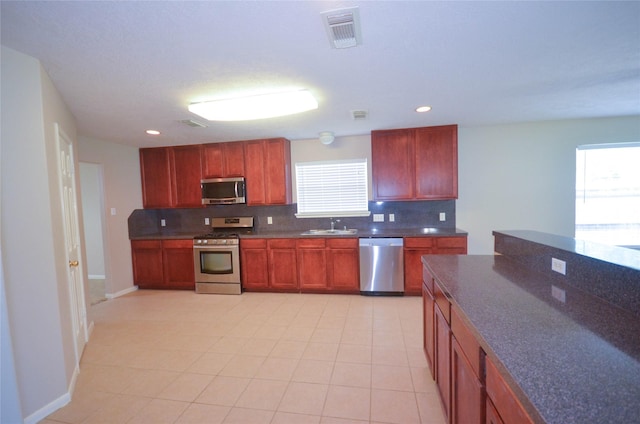 6906 Grant Dr, Magnolia, TX 77354 - kitchen with stainless steel appliances, decorative backsplash, dark countertops, recessed lighting, and light tile patterned floors