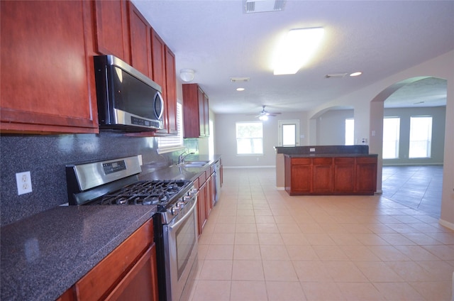6906 Grant Dr, Magnolia, TX 77354 - kitchen with appliances with stainless steel finishes, light tile patterned floors, a ceiling fan, tasteful backsplash, and dark countertops